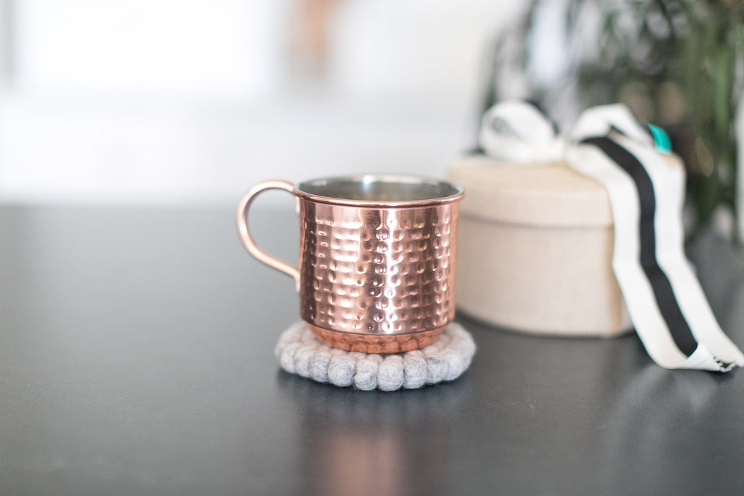 Copper mug on a textured coaster with a blurred background