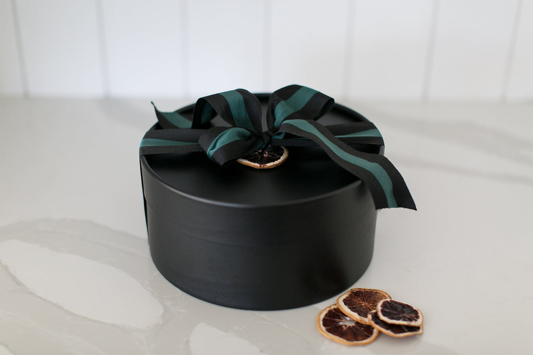 Black gift box with a green ribbon on a white surface