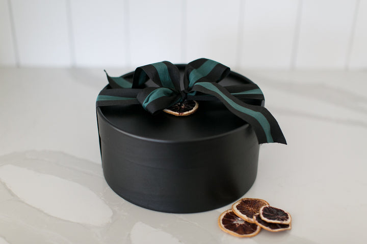 Black gift box with a green ribbon on a white surface