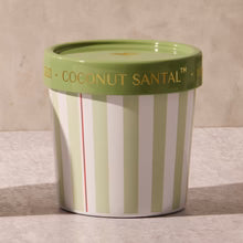 Green and white striped candle container with a green lid on a marble surface