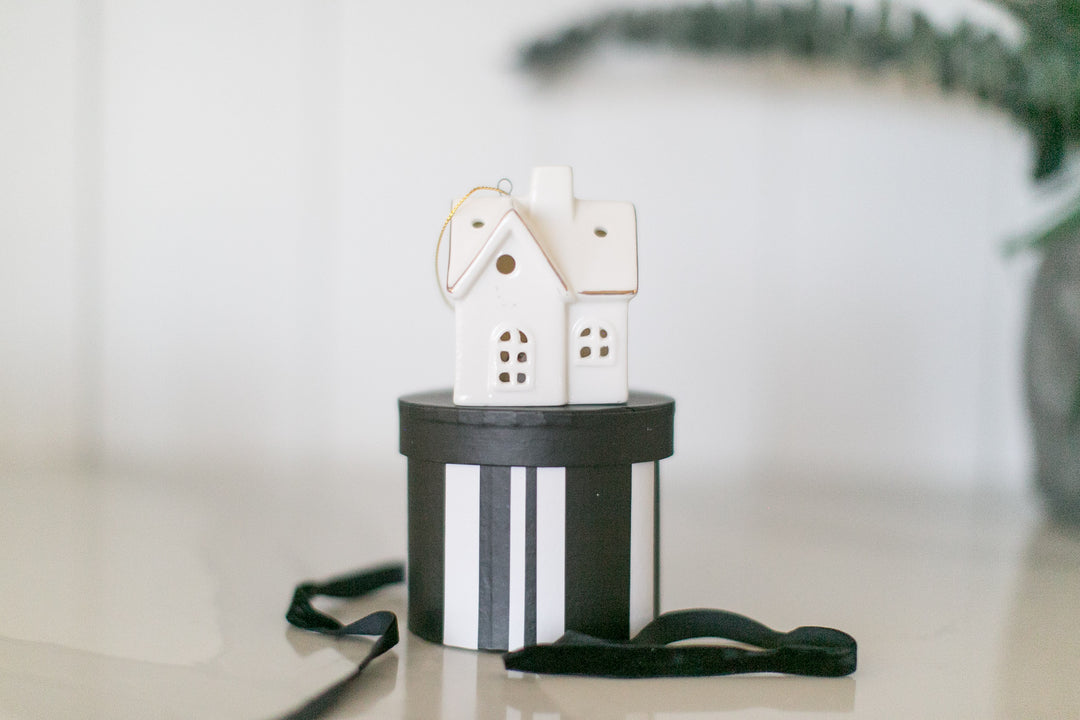 Decorative house ornament on a black and white striped box with a blurred background