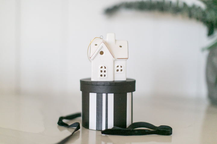 Decorative house ornament on a black and white striped box with a blurred background