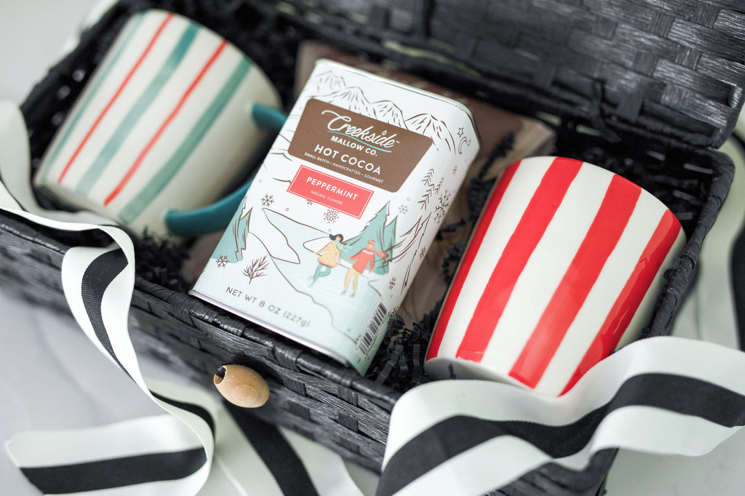 Creekside Mallow Co. Peppermint Hot Cocoa mix in a tin with two stoneware mugs in red strip and the other in a green and red stripe. Black hinge top gift box. Reusable. Sustainable. Gift box ready to ship from Mercy Forest Co. in Independence MN. 