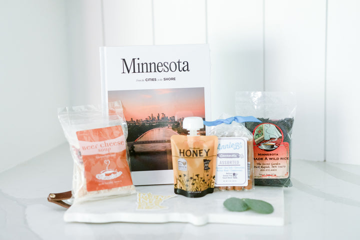 The coffee table book 'Minnesota: From the Cities to the Shore' elegantly displayed in the gift box, an ideal choice for realtors to share with clients as a memorable home anniversary gift. This book highlights the beauty and culture of Minnesota.