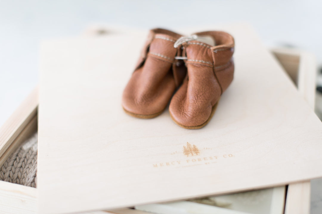 Brown leather moccasins on top of a customizable pine keepsake box.