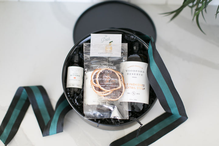 Gift basket with products including a bottle, a box, and a bracelet on a white surface.