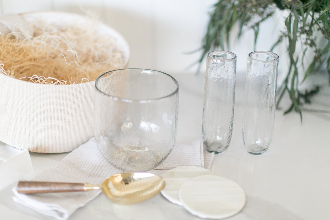 Elevated home entertaining gift with glass ice bucket, flutes and coasters on a marble counter