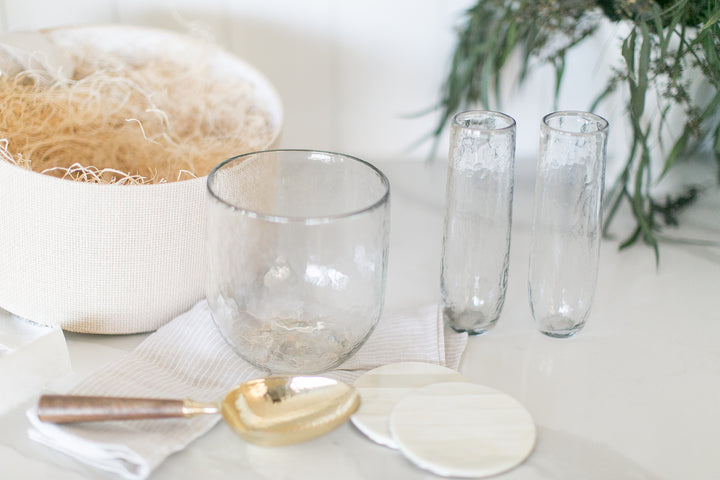 Elevated home entertaining gift with glass ice bucket, flutes and coasters on a marble counter