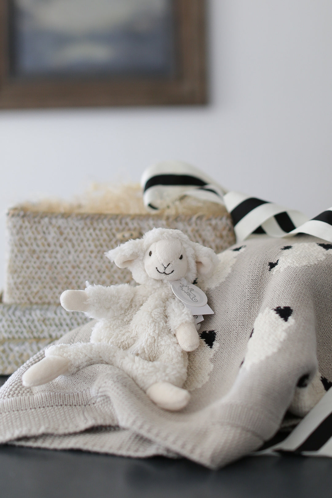 baby gift box with knit lamb baby blanket and lamb plush lovie. set on a white marble countertop and white shiplap backdrop.