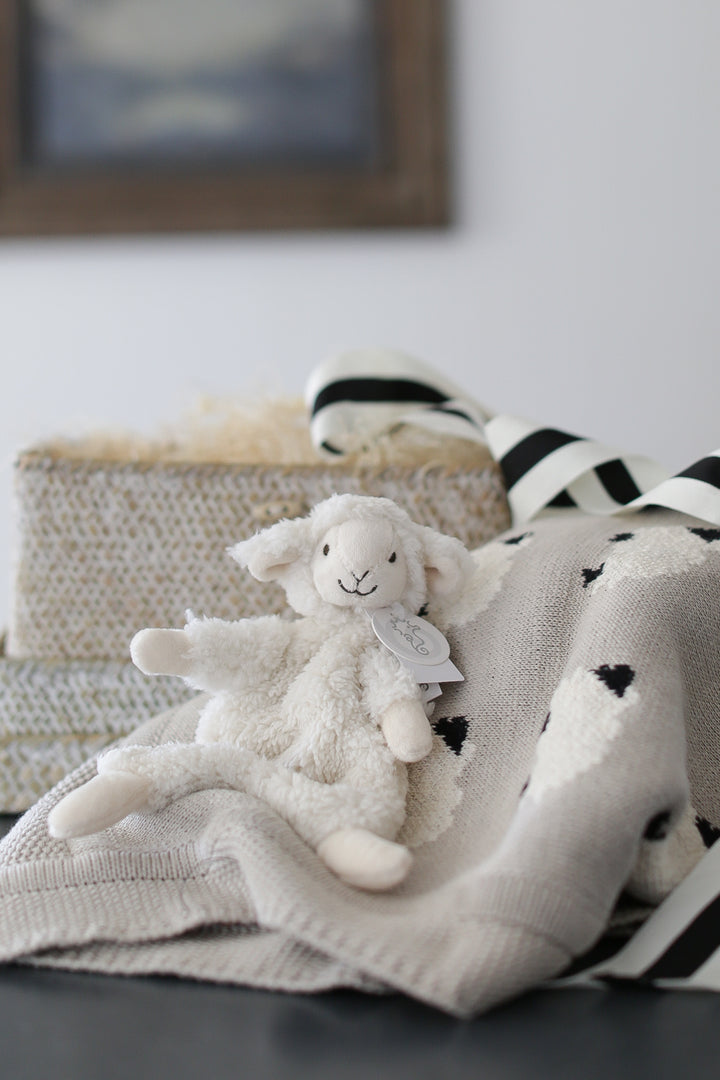 baby gift box with knit lamb baby blanket and lamb plush lovie. set on a white marble countertop and white shiplap backdrop.