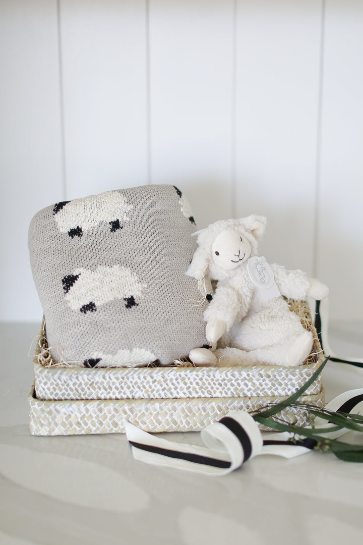 baby gift box with knit lamb baby blanket and lamb plush lovie. set on a white marble countertop and white shiplap backdrop.