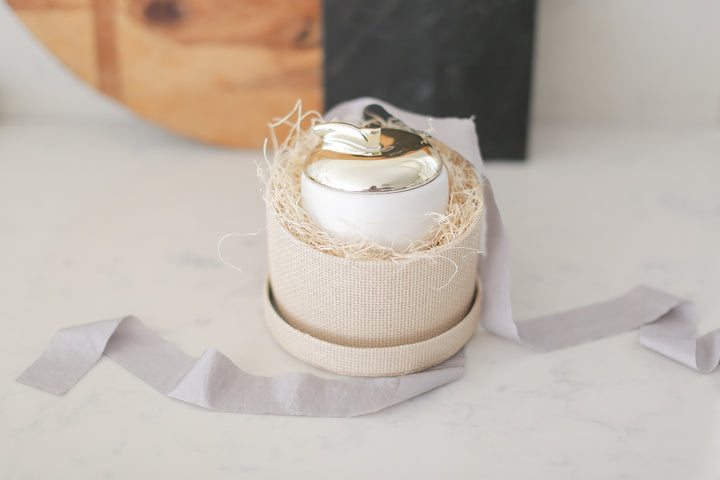 Apple candle with brass painted ceramic top. Woven paper box with lid. 