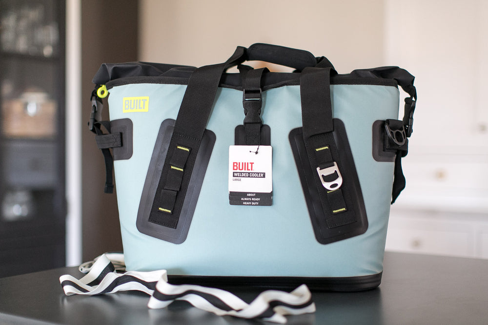 Light blue cooler bag with black straps on a table, featuring the 'Built' brand.