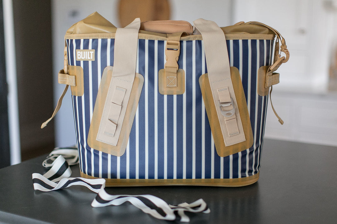 Blue and white striped bag with beige straps on a dark surface