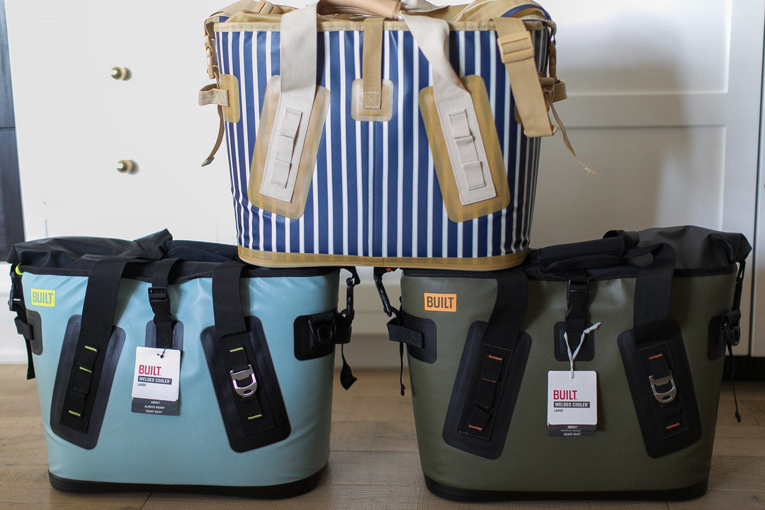 Three bags, two blue and one green, with tags on a wooden floor.