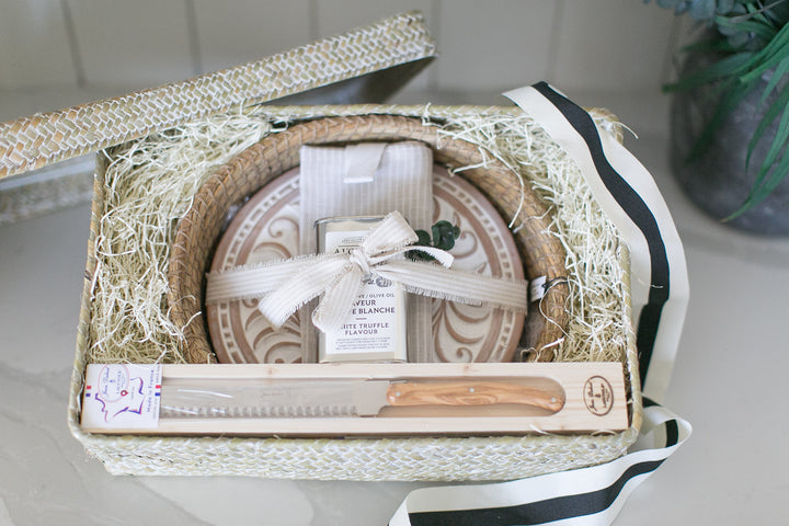 Gift basket with plates, knife, and decorative items on a white surface