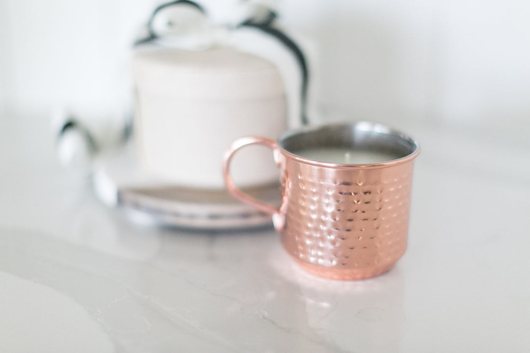 Rose gold mug with tea on a white surface