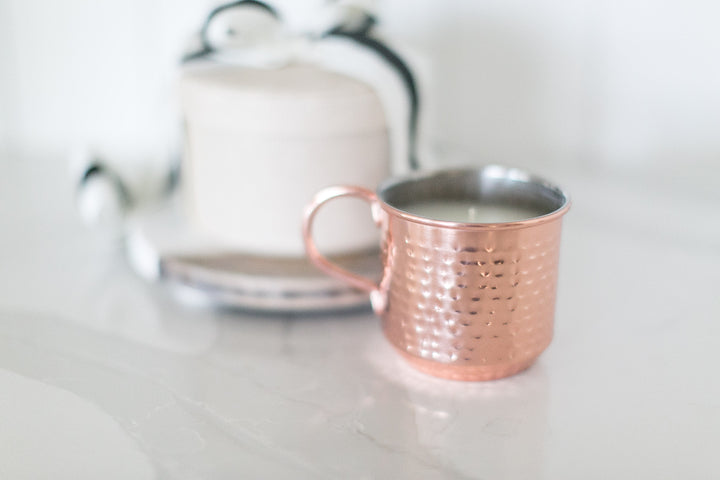 Rose gold mug with tea on a white surface