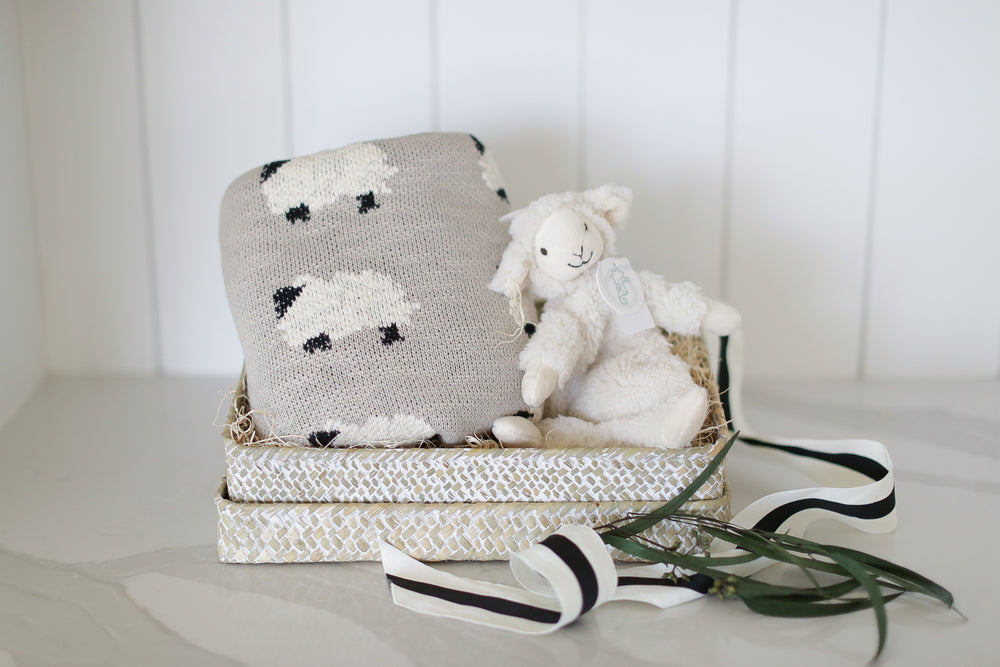 baby gift box with knit lamb baby blanket and lamb plush lovie. set on a white marble countertop and white shiplap backdrop.