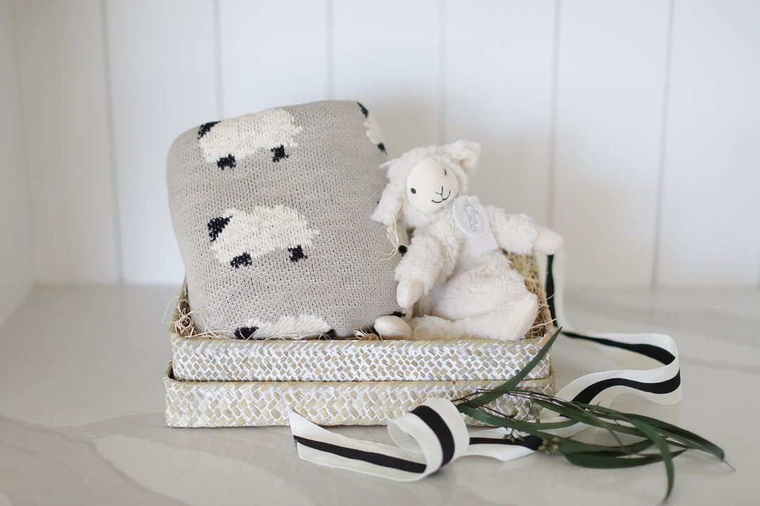 baby gift box with knit lamb baby blanket and lamb plush lovie. set on a white marble countertop and white shiplap backdrop.