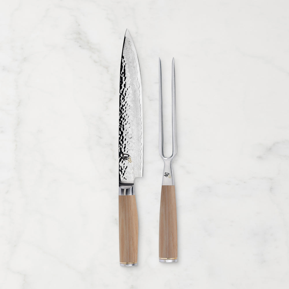 Shun Premier Carving knife and fork with blonde handle on white marble backdrop