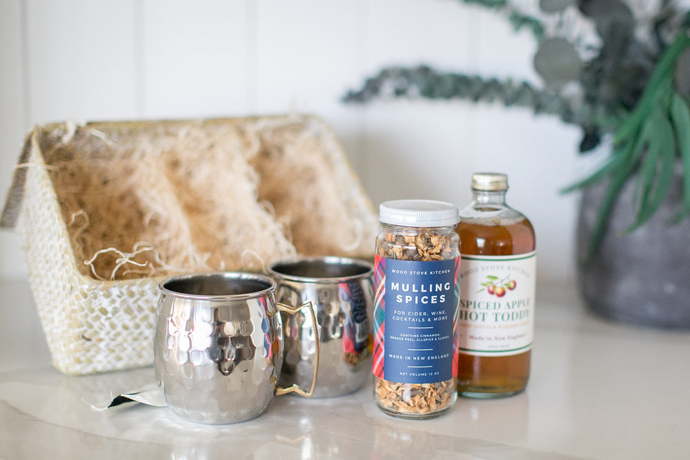 Thomas gift box with mulling spices and hot toddy mix on a white marble counter with decorative items.