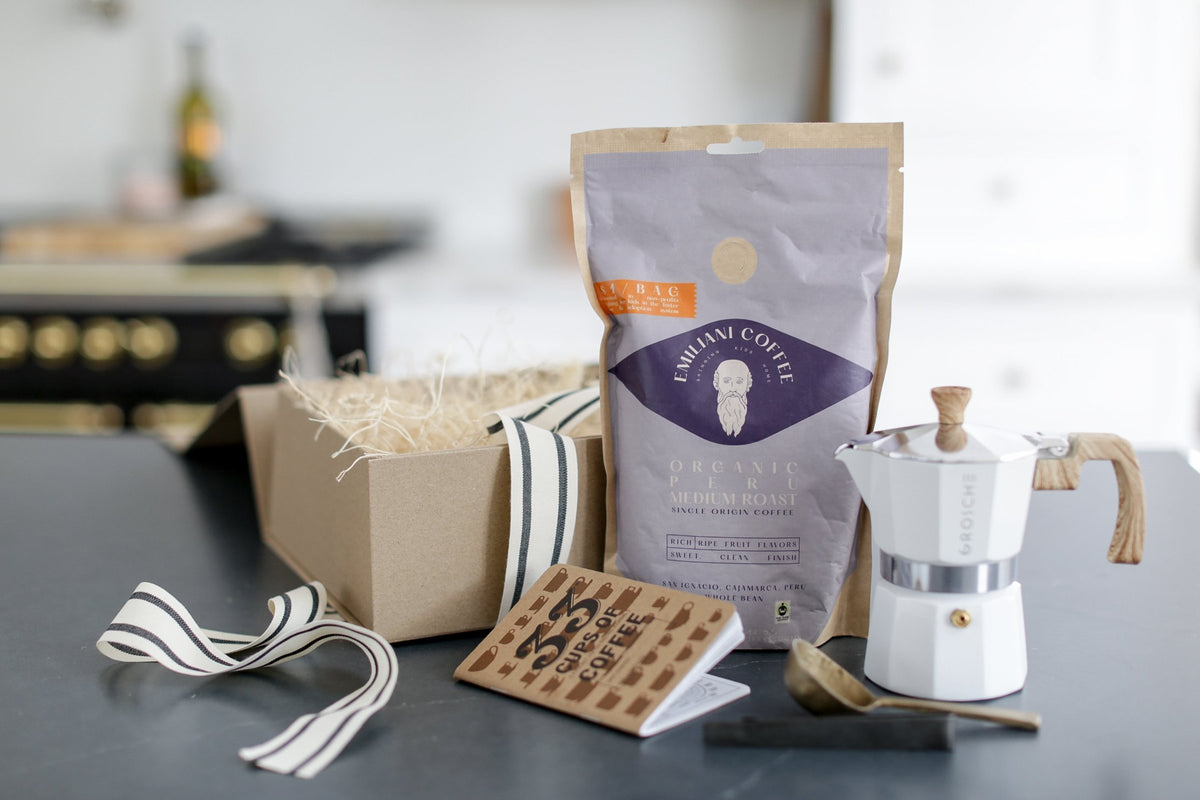 Emiliani coffee bag, moka pot and a kraft gift box with striped ribbon.