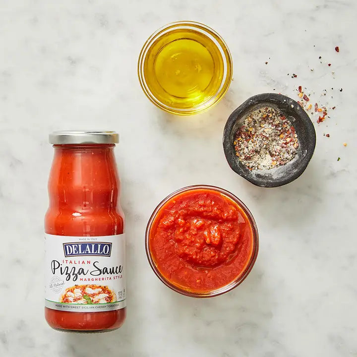 Arranged on a white countertop is a glass jar of Marinara sauce and other oils and other seasonings.