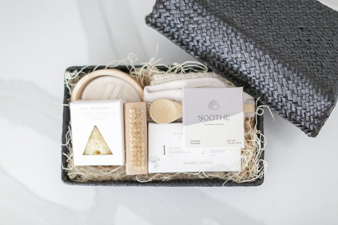 Comfort gift for those in need of self care, includes Nash and Jones clay mask, sea sponge and shower steamers. Gift is ready to ship in black woven basket with lid and ribbon. Mercy Forest Co. gifting. Custom curated gifts that are ready to ship and be delivered, spa inspired gift box with shower steamer options of either lavender or eucalyptus 