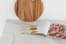 Load image into Gallery viewer, Wood charcuterie board with personalization available, Appetizer and charcuterie cookbook, idea book for charcuterie board, brass and rattan wrapped cheese utensils, white countertop, Mercy Forest Co., custom gifting for realtors, on-demand ready-to-ship gifts, packaged gift box