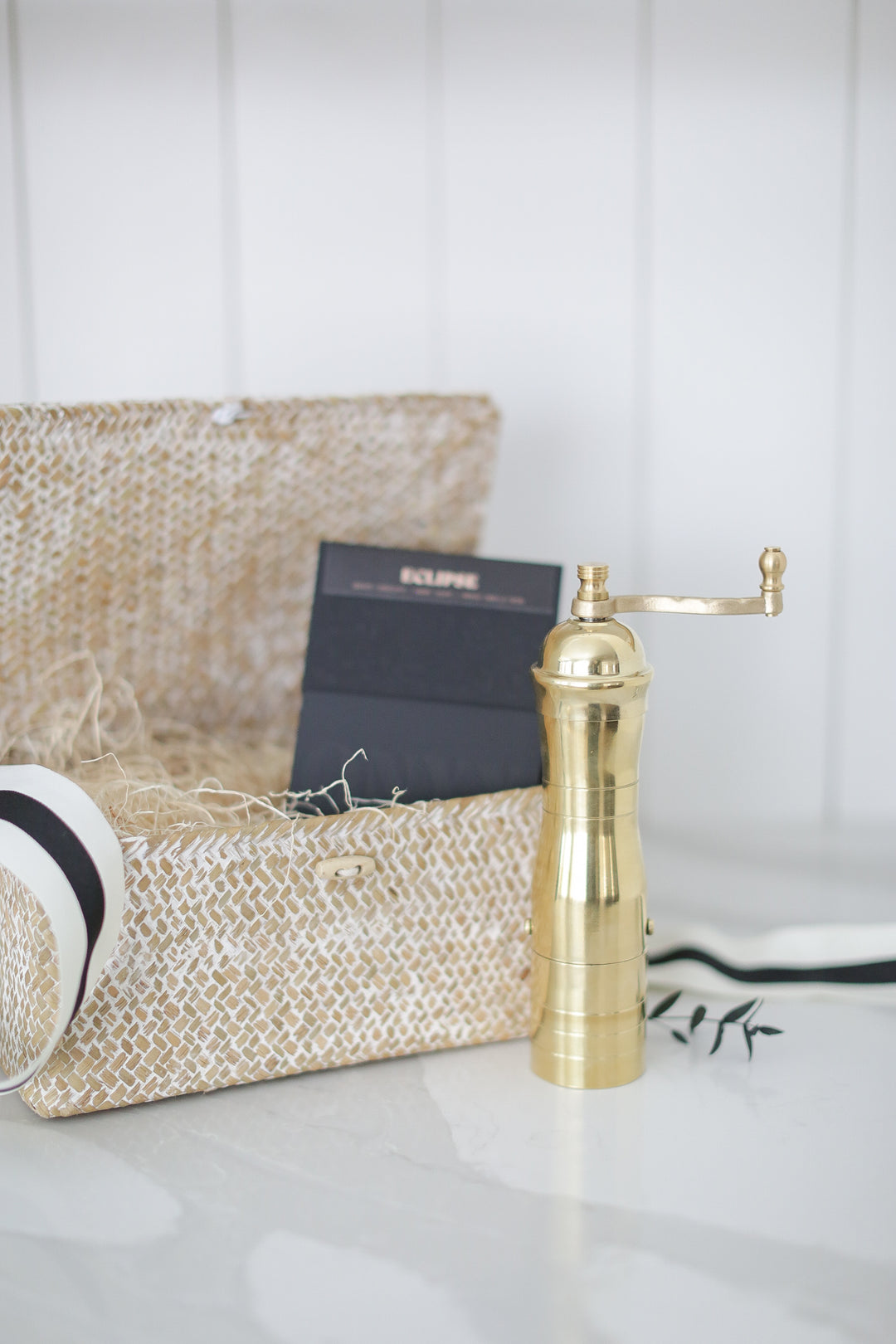 A gold coffee grinder by a decretive box.