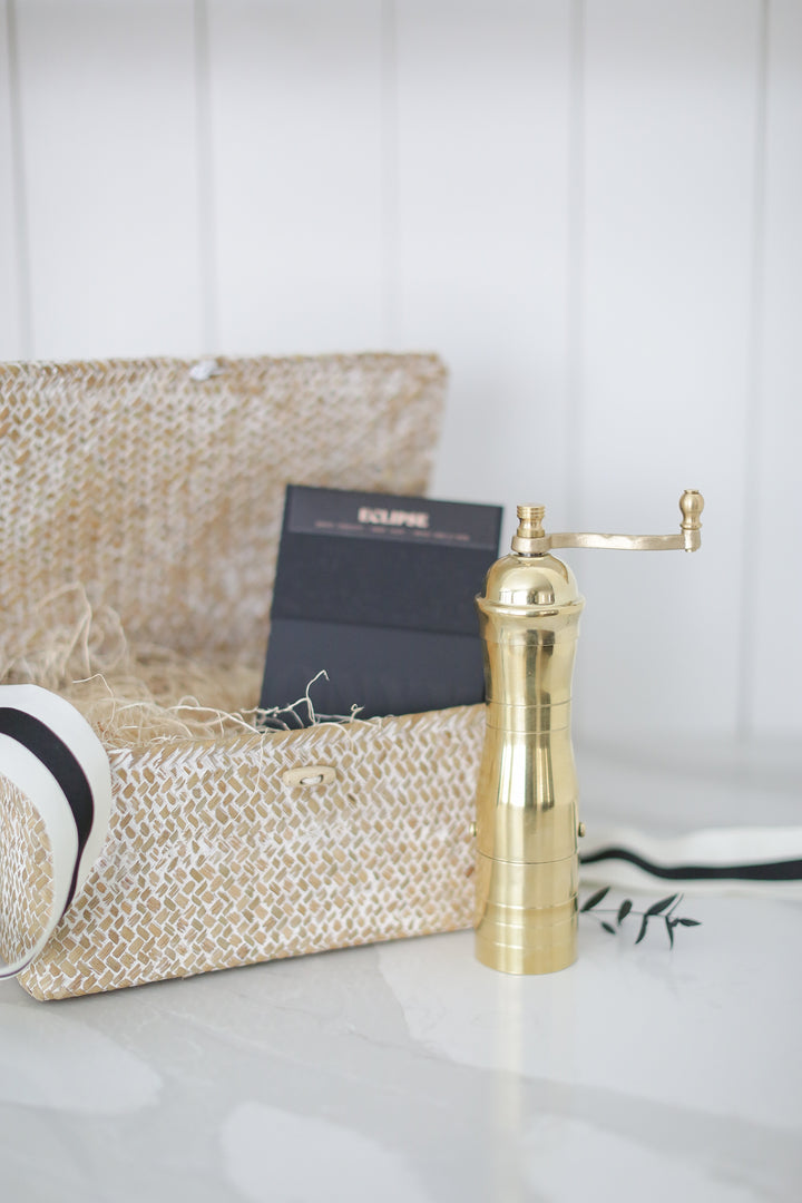 A gold coffee grinder by a decretive box.