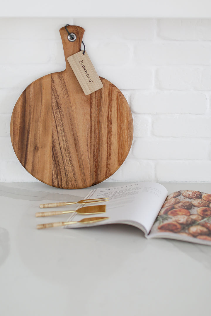 Wood charcuterie board with personalization available, Appetizer and charcuterie cookbook, idea book for charcuterie board, brass and rattan wrapped cheese utensils, white countertop, Mercy Forest Co., custom gifting for realtors, on-demand ready-to-ship gifts, packaged gift box