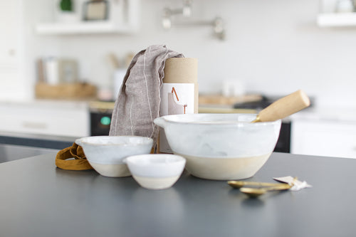 Custom curated gift box with baking bowls and utensils,  stoneware stacking baking bowls, brass wire whisk, brass measuring spoons, striped apron, Mercy Forest Co., real estate gifting, client gifting ideas