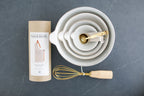custom cooking bowls, apron, and measuring spoons gift box, Custom curated gift box with baking bowls and utensils,  stoneware stacking baking bowls, brass wire whisk, brass measuring spoons, striped apron, Mercy Forest Co., real estate gifting, client gifting ideas, soapstone countertop