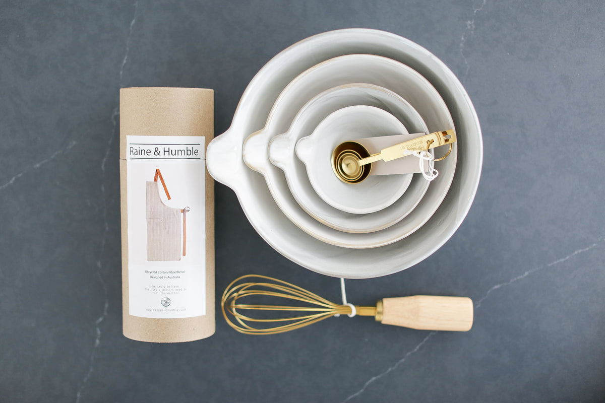 custom cooking bowls, apron, and measuring spoons gift box, Custom curated gift box with baking bowls and utensils,  stoneware stacking baking bowls, brass wire whisk, brass measuring spoons, striped apron, Mercy Forest Co., real estate gifting, client gifting ideas, soapstone countertop